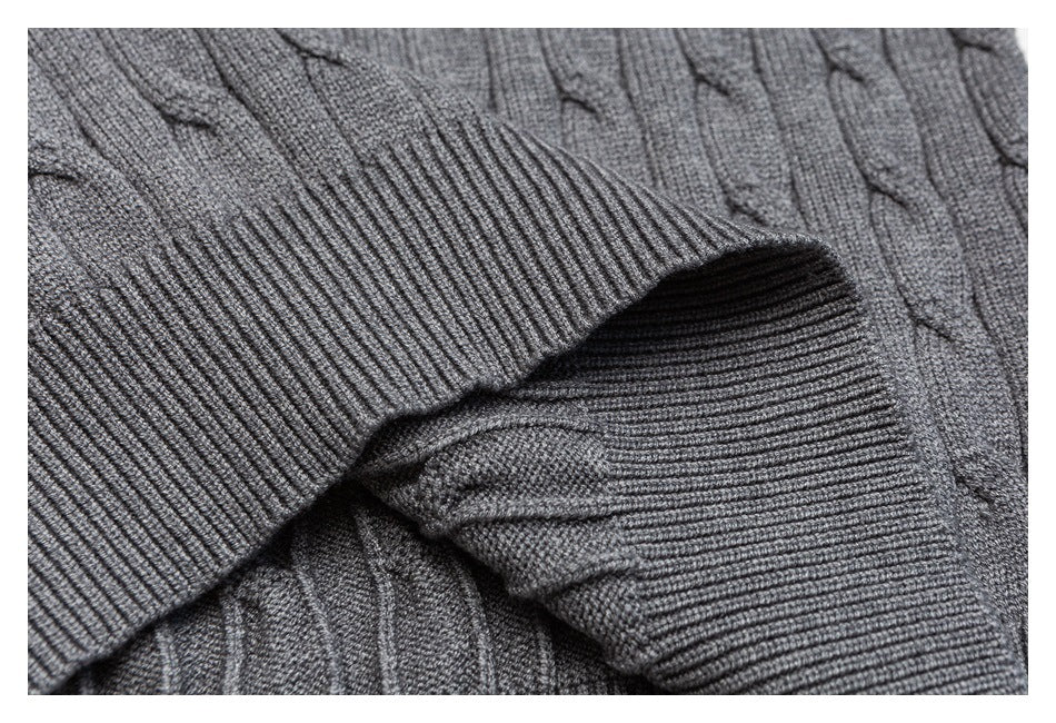 Close-up of a gray cable-knit sweater with overlapping ribbed cuffs and raised cable patterns.