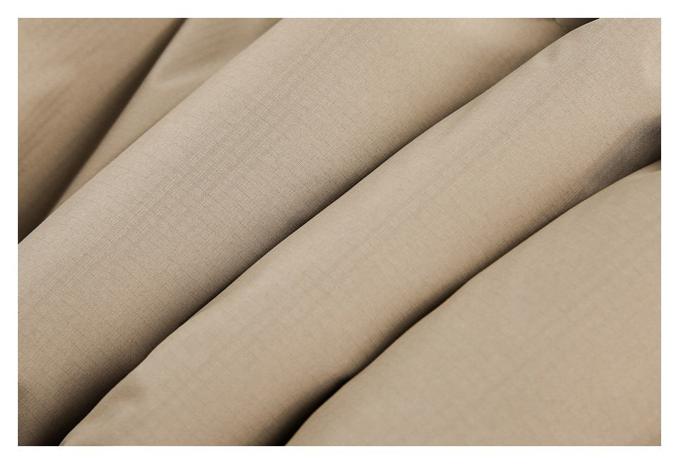 Close-up of tan garment fabric arranged in folds, showing its subtle grid texture.