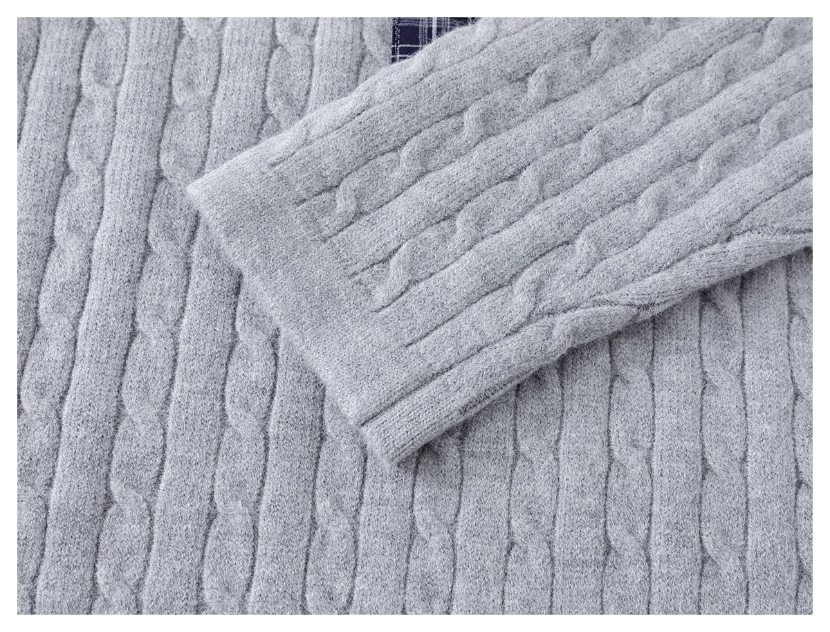 Close-up of a cable-knit sleeve laid across the light gray garment.