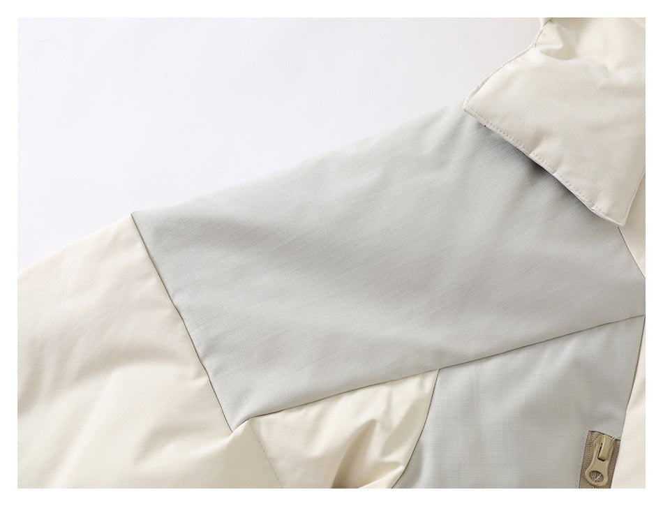 Close-up of a cream jacket with a light gray shoulder panel and tan zipper hardware.