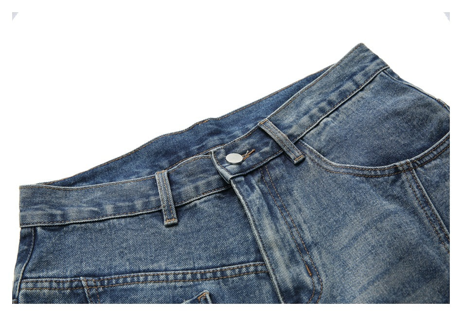 Close-up of blue washed jeans showing the waistband, belt loops, button, fly, and curved front pocket.