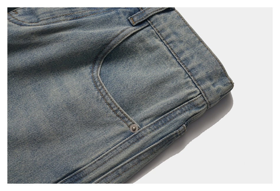 Close-up of a front pocket, rivet, side seam, and waistband on faded blue jeans.