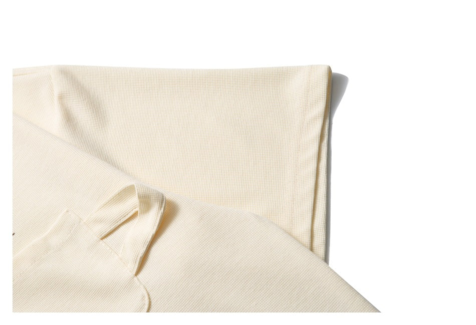 Close-up of folded ivory knit fabric with a visible seam and sleeve edge.