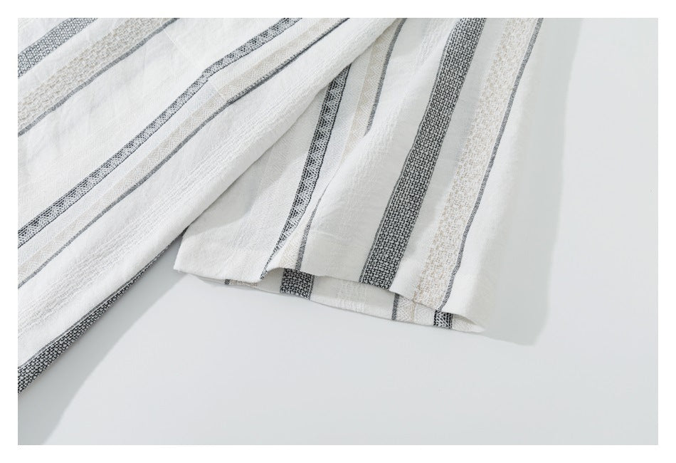 Close-up of the striped shirt's folded edge and stitching against a white background.
