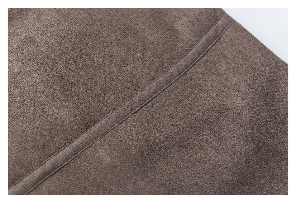 Close-up of a brown jacket showing a diagonal stitched seam and textured surface.