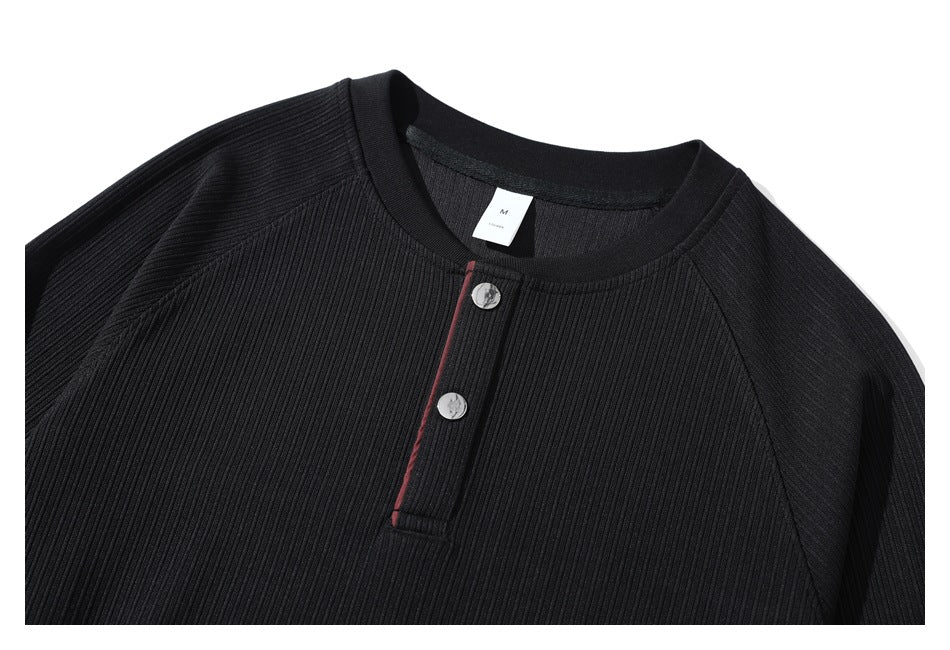 Close-up of a black ribbed henley neckline with two buttons and narrow red placket trim.