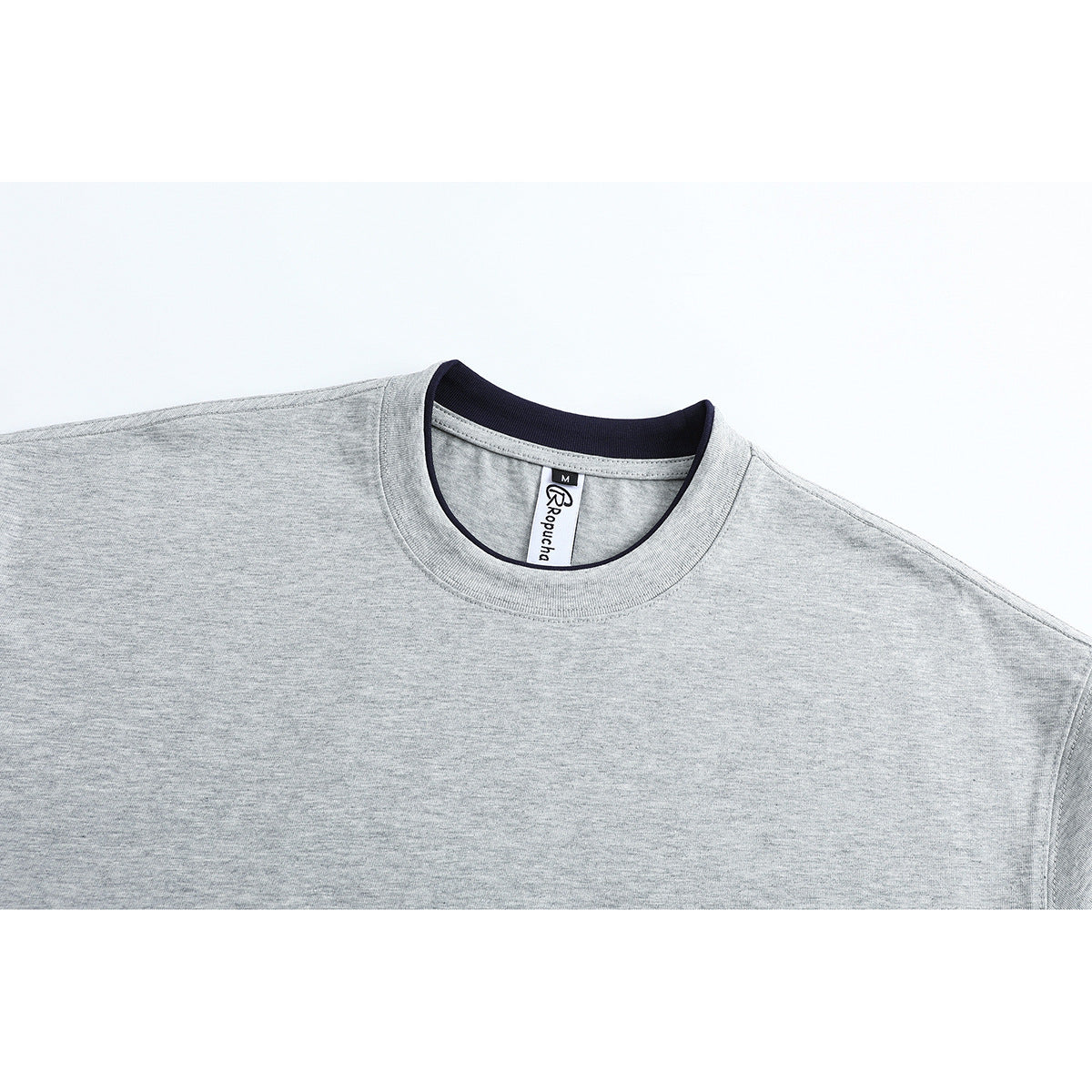 Close-up of a light gray crew-neck T-shirt showing the ribbed collar and inner neck label.