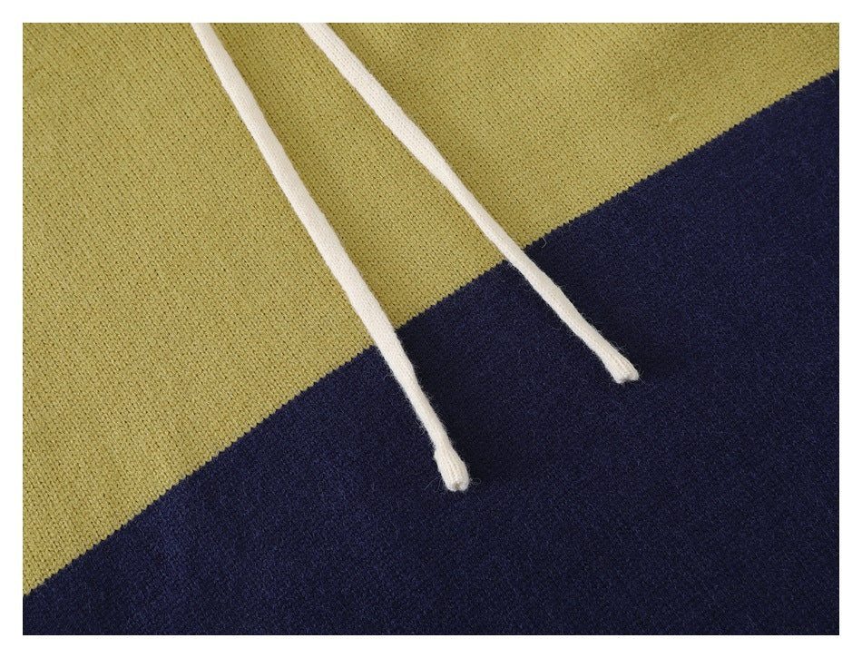 Close-up of white hoodie drawstrings over pale yellow-green and navy color-blocked knit fabric.