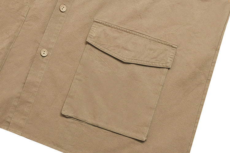 Close-up of a tan shirt's button-flap chest pocket and front stitching.