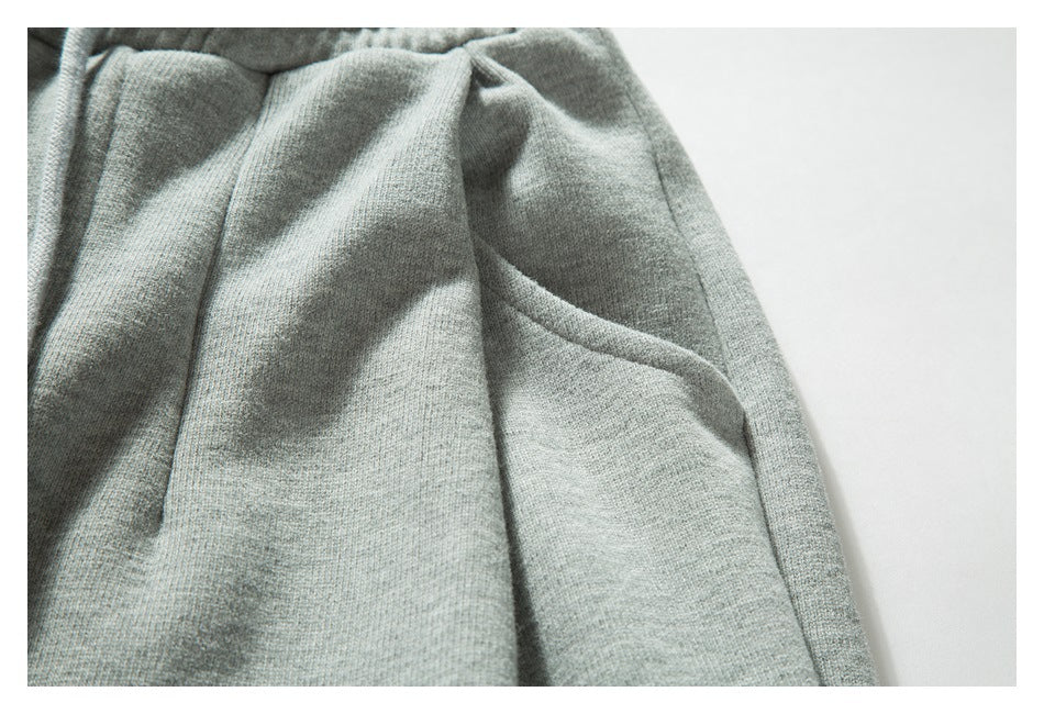 Close-up of a light gray knit garment showing a curved pocket opening and stitched seams.