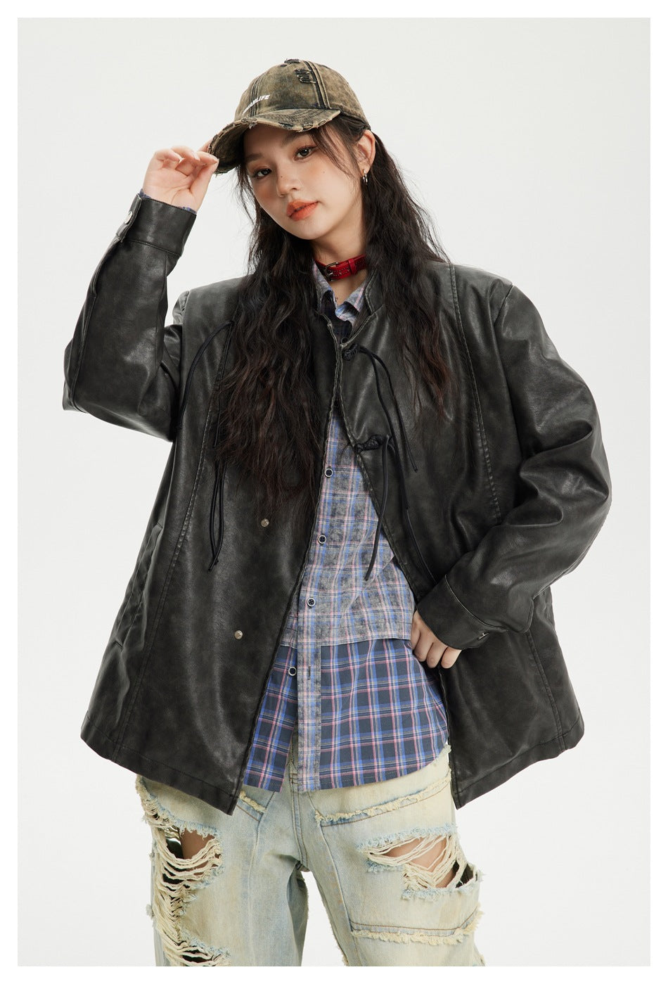 Model wearing an oversized charcoal-black jacket with frog closures over a blue plaid shirt, shown from the front.