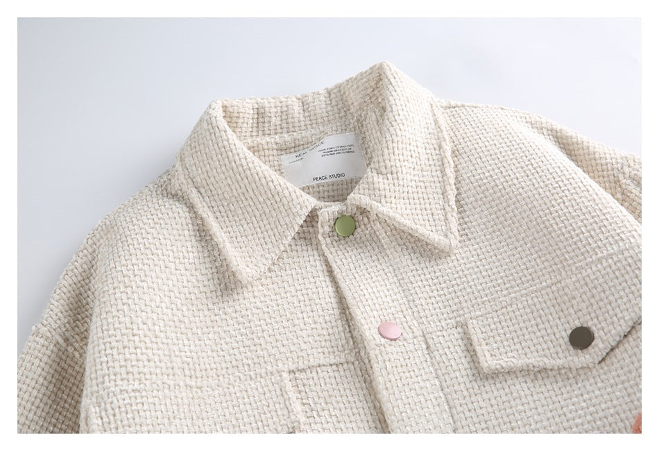 Close-up of the ivory jacket's woven texture, collar, colorful buttons, and flap chest pocket.