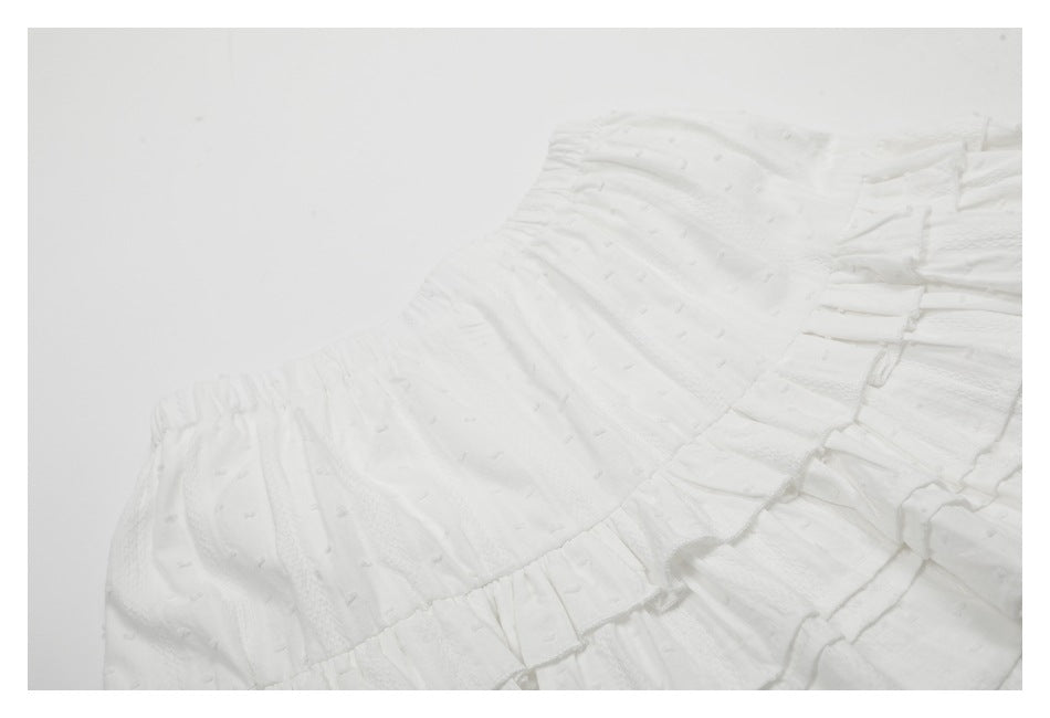 Close-up of the gathered waistband and tiered ruffles on a white skirt.