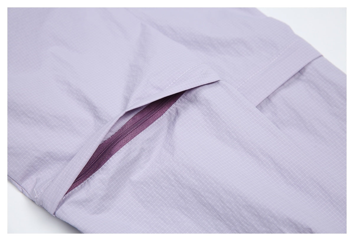 Close-up of a plum zipper pocket beneath a flap on a lavender grid-patterned garment.