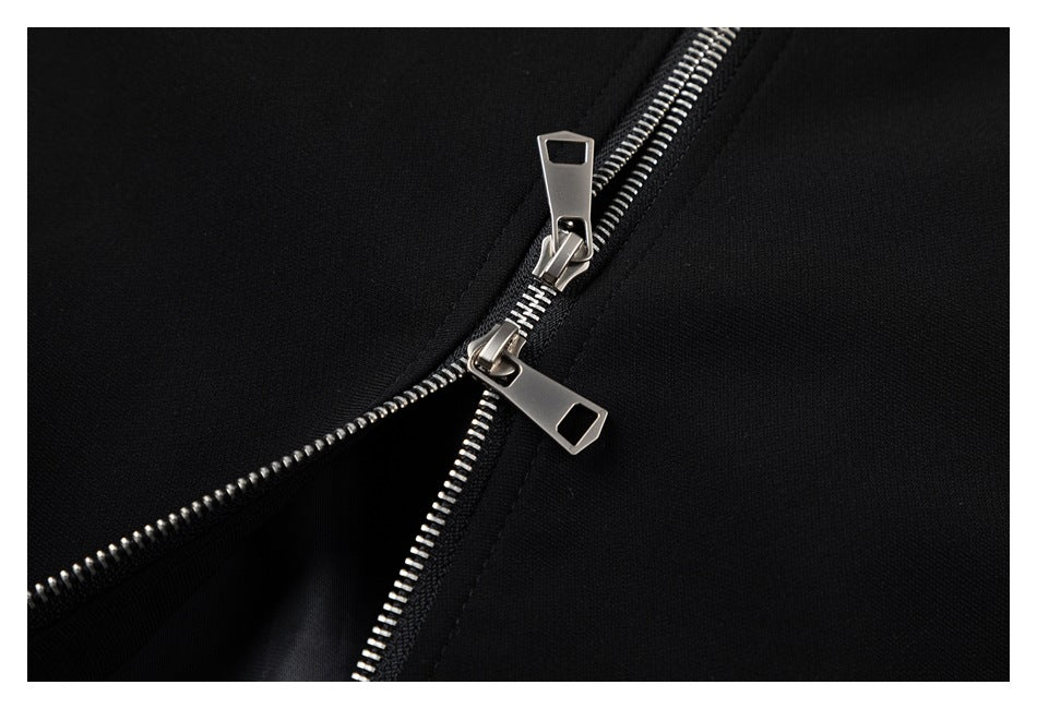 Close-up of two silver zipper sliders on black garment fabric.