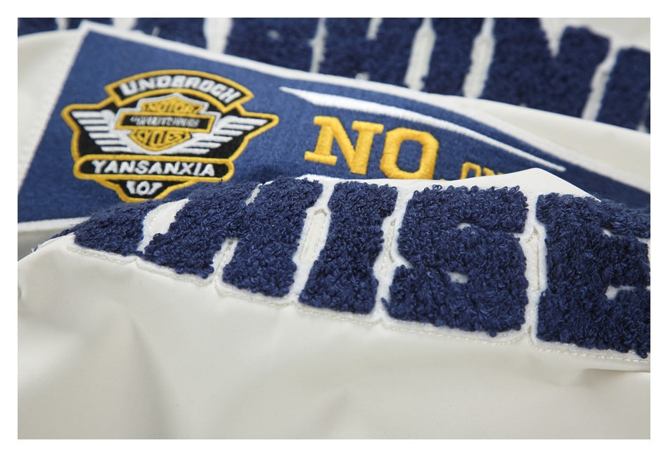 Close-up of raised navy chenille lettering and a navy-and-yellow embroidered patch on white fabric.