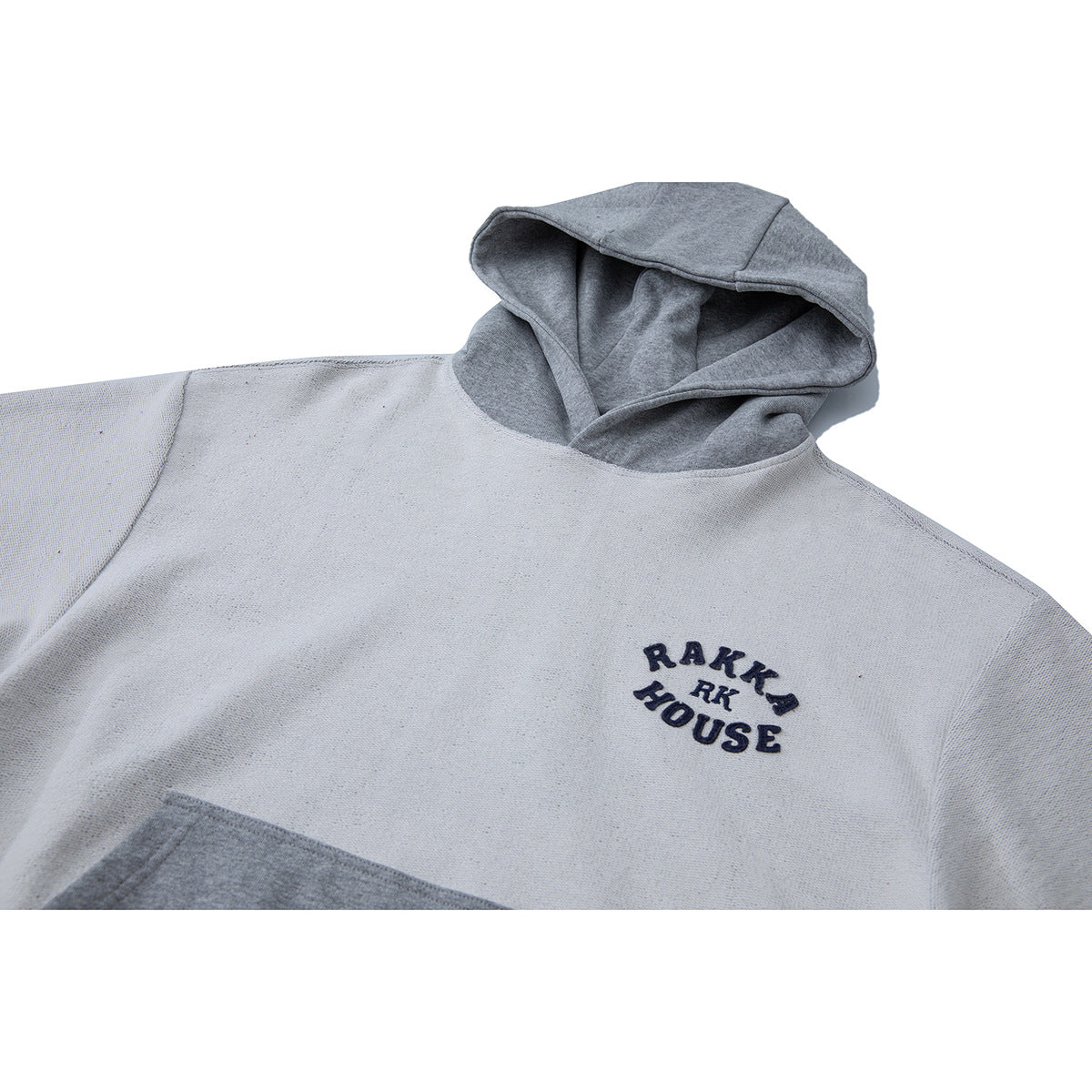 Close-up of a light gray hoodie with a darker gray hood and embroidered text on the chest.