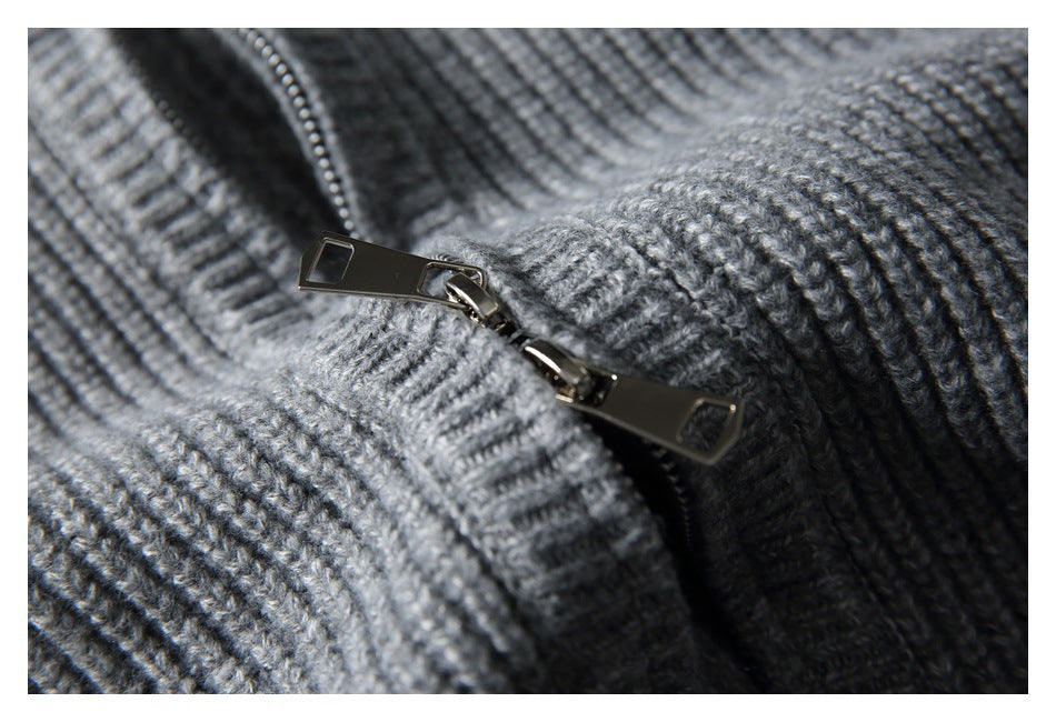 Macro view of the metal zipper pull and ribbed gray knit sweater fabric.