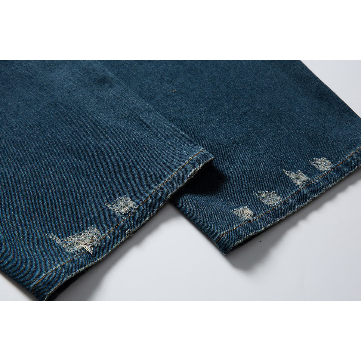 Close-up of dark blue jeans legs and hems with scattered distressed patches.