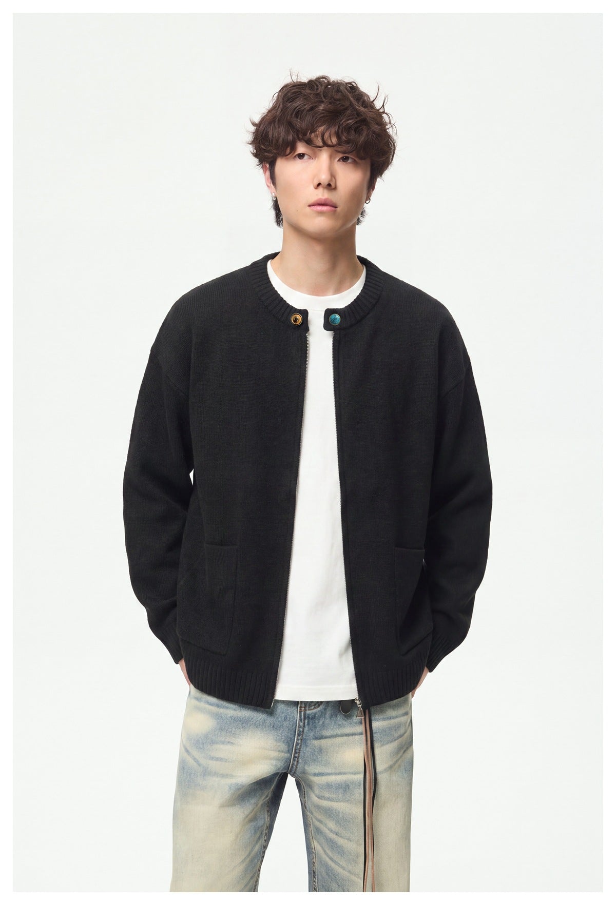 Model wearing an open black knit cardigan with a front zipper, contrast buttons, ribbed trim and two patch pockets.