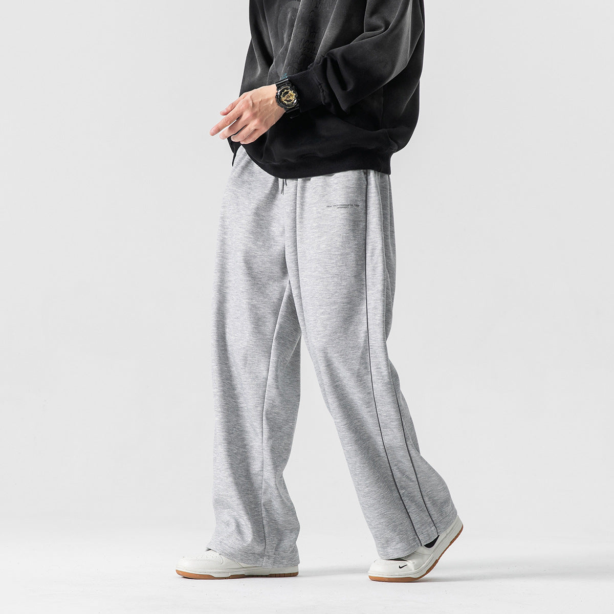 Model wearing light gray wide-leg pants with dark piping, shown at a slight angle.
