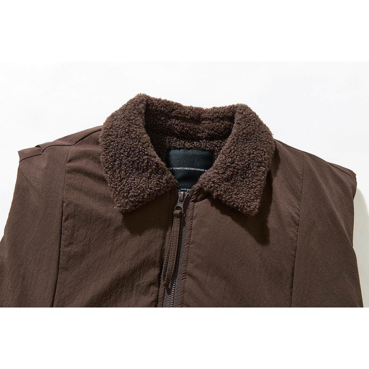 Close-up of a dark brown sleeveless vest with a textured fleece collar and front zipper.