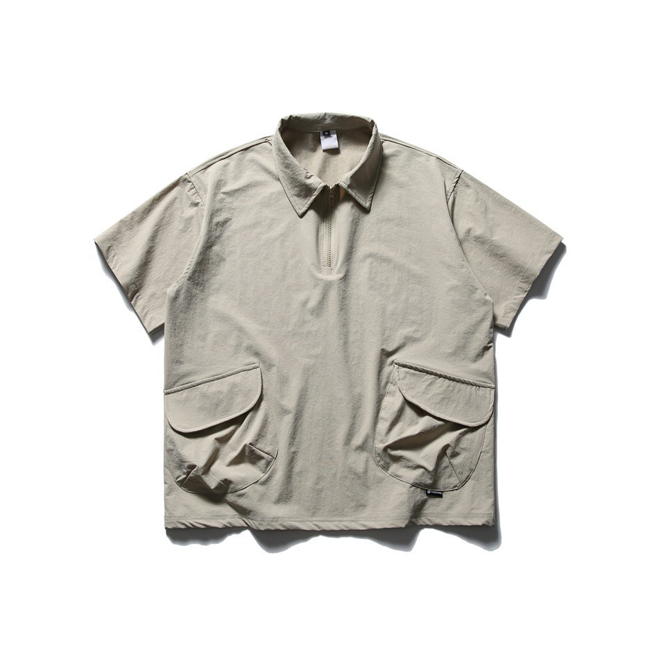 Light khaki short-sleeve quarter-zip polo shirt with collar and two large flap pockets, laid flat, front view