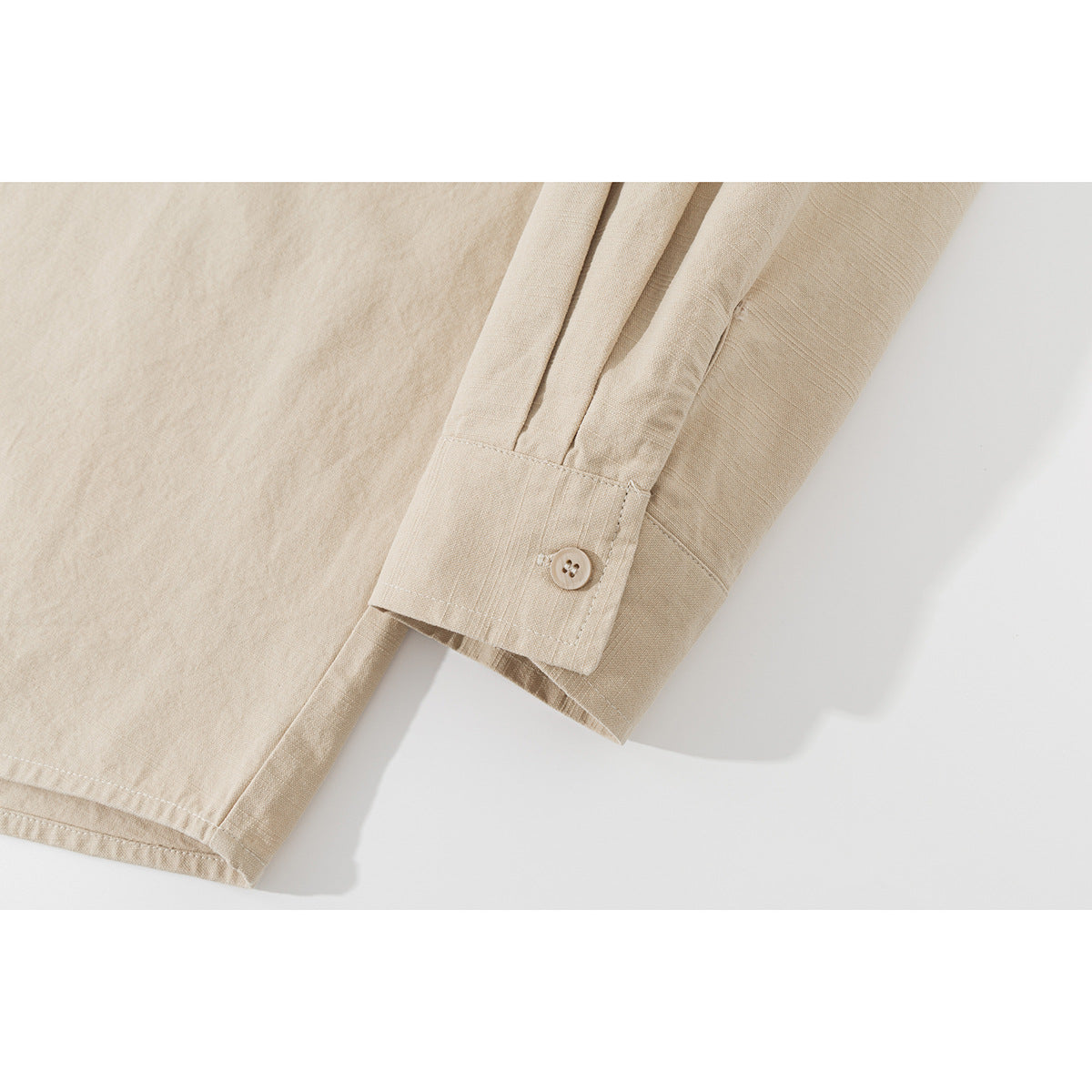 Close-up of a beige shirt sleeve cuff with a button and stitched seams.