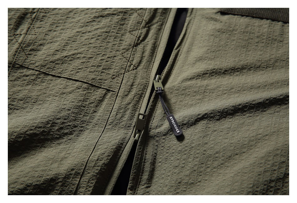 Close-up of the olive jacket's front zipper, branded pull tab, and textured fabric.