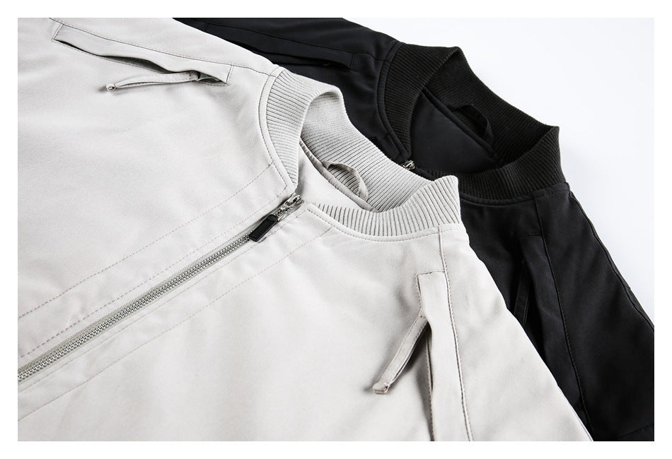 Close-up of light gray and black bomber jackets, showing the ribbed collars, front zippers and sleeve details.