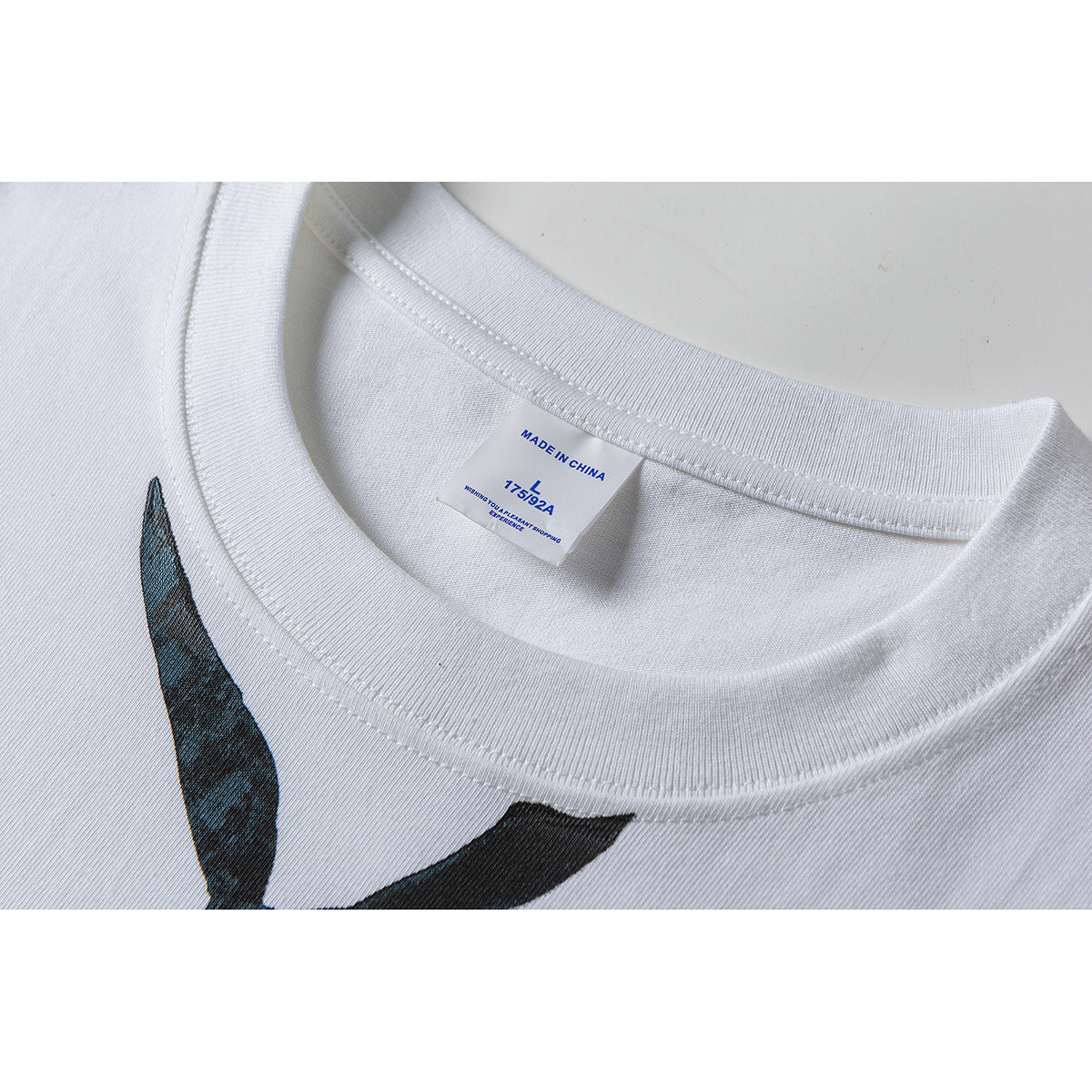 Close-up of a white T-shirt neckline and collar label marked Made in China and size L, with part of a dark graphic visible.
