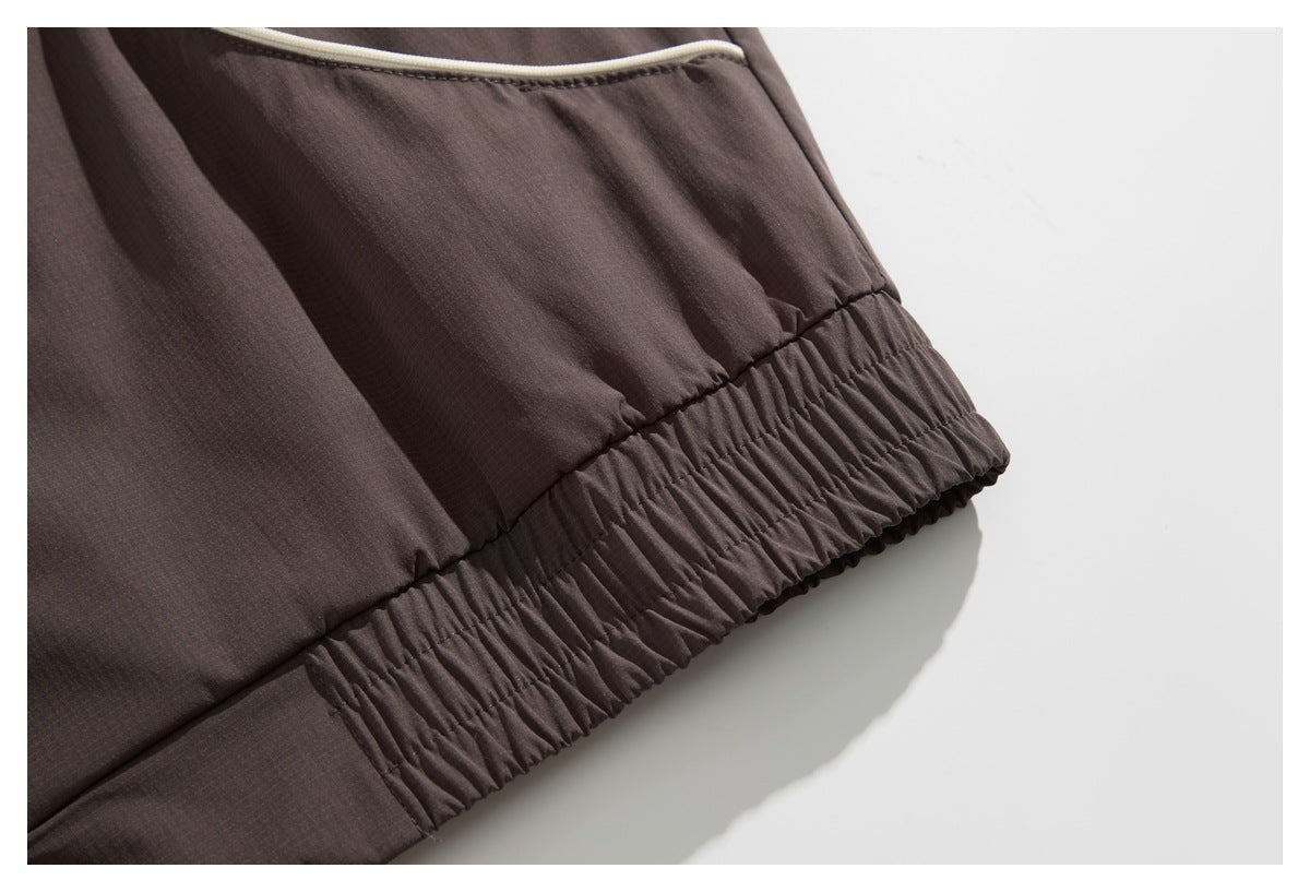 Close-up of a dark brown garment's cream-piped pocket and gathered elastic hem.