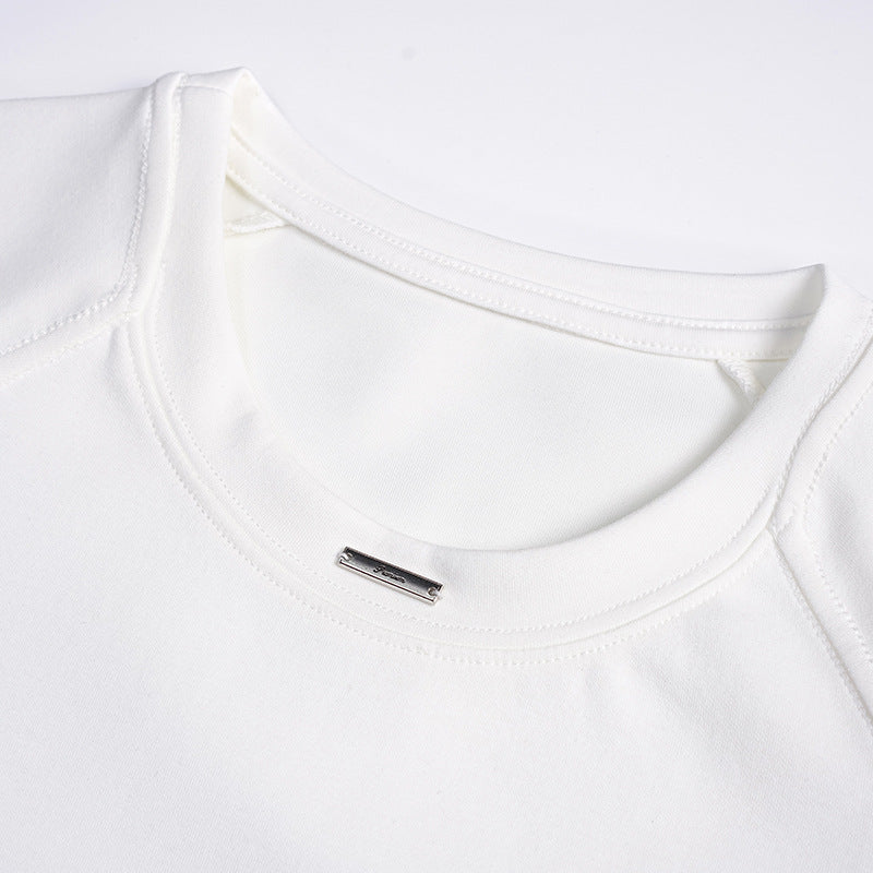 Close-up of a white T-shirt's crew neckline and shoulder seams, with a small metal label.