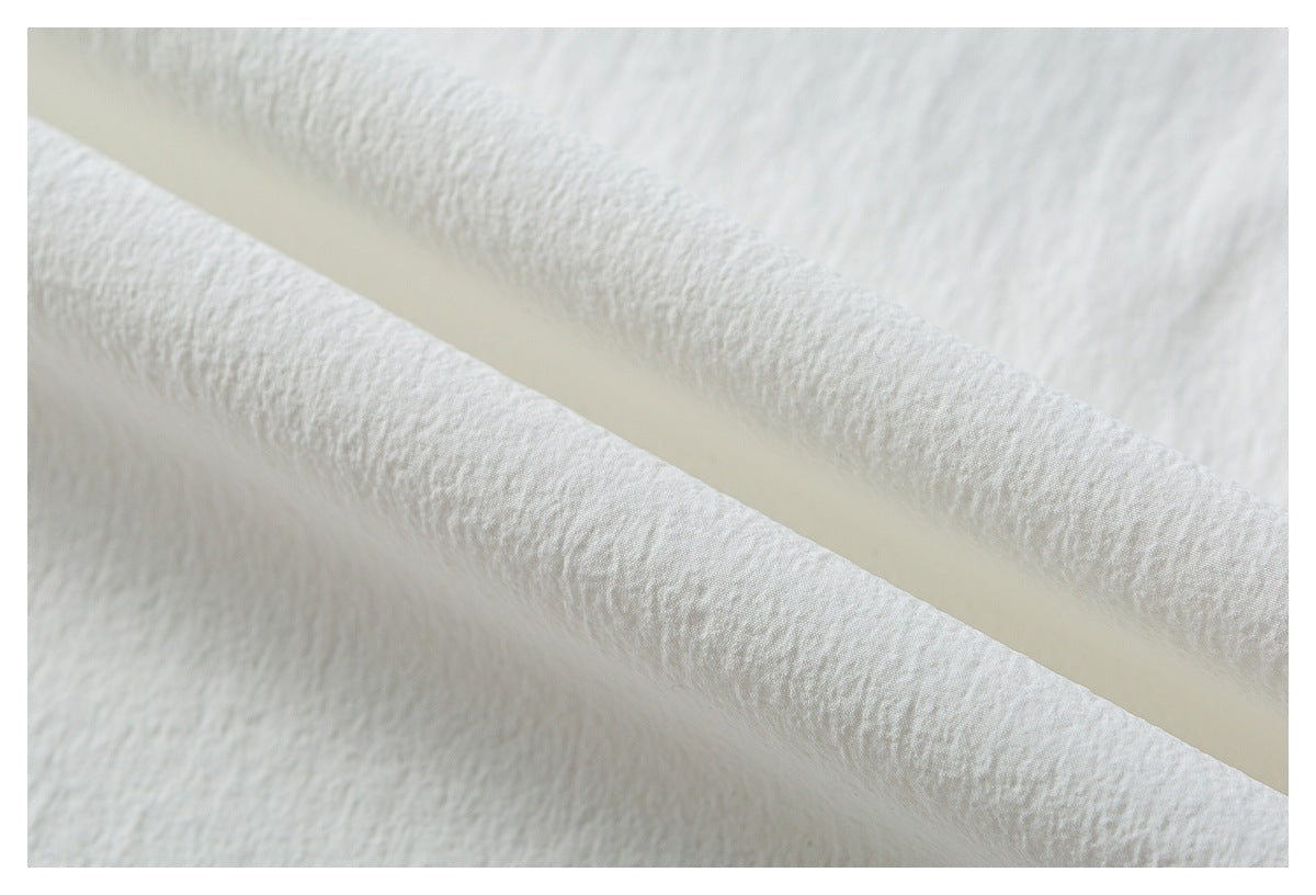 Close-up of softly textured white fabric folded to show its surface.