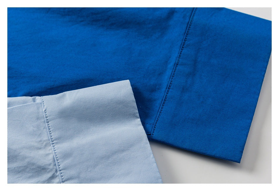Close-up of a blue shirt sleeve beside a pale blue fabric panel, showing the seams and stitching.