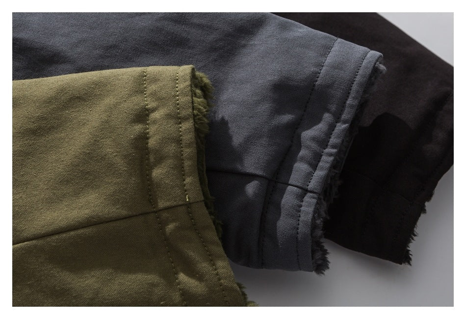 Close-up of coat sleeve cuffs showing stitched hems and contrasting gray, olive green and black fabric sections.
