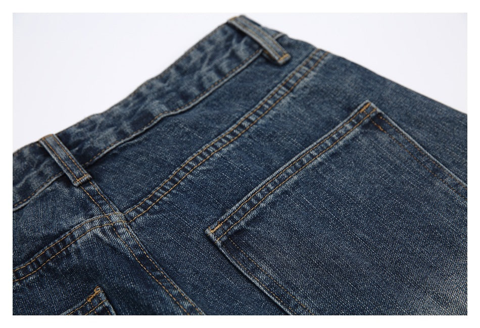 Close view of the back waistband and rear pocket of dark blue jeans with contrast stitching.