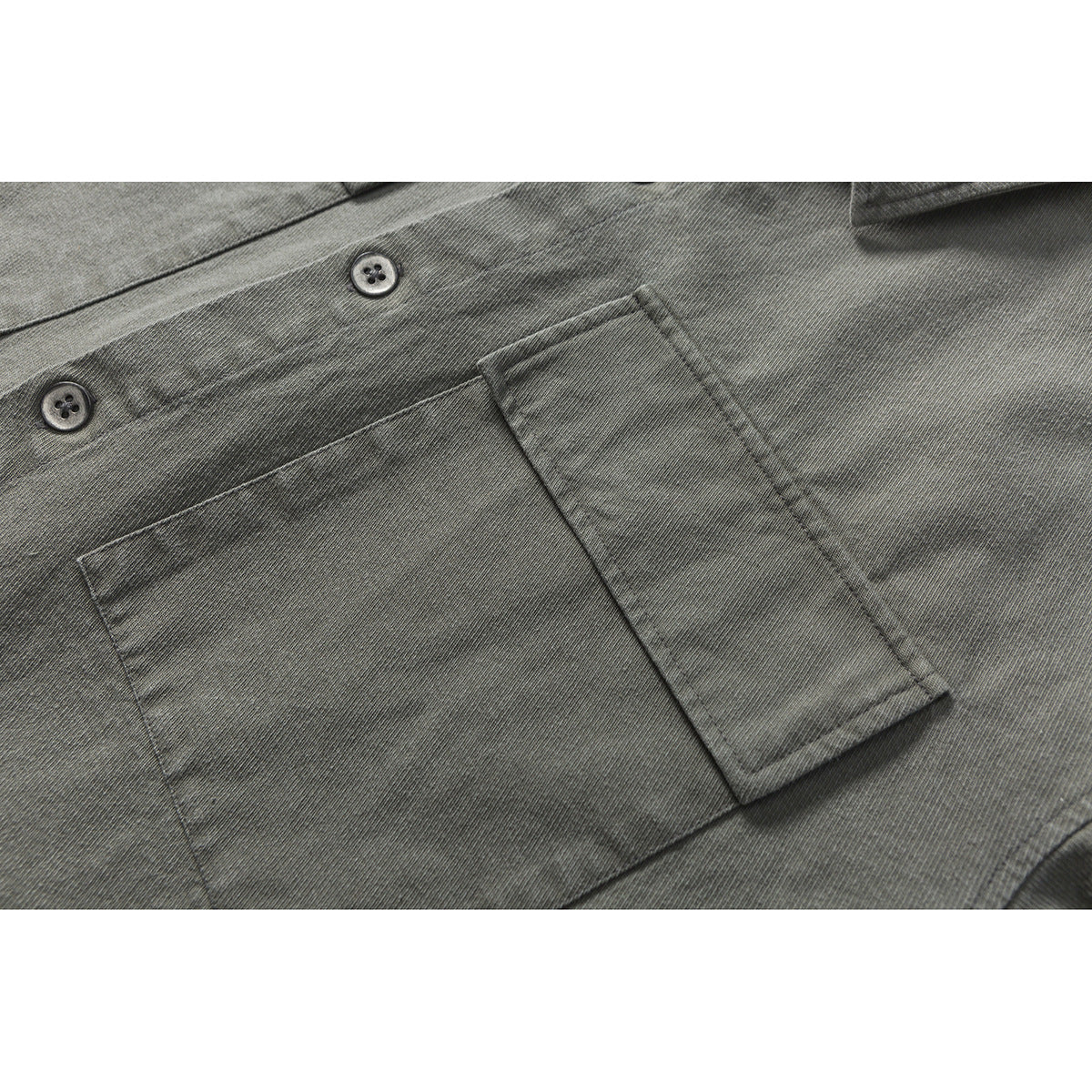 Close-up of a charcoal gray shirt’s button placket and rectangular chest pocket.