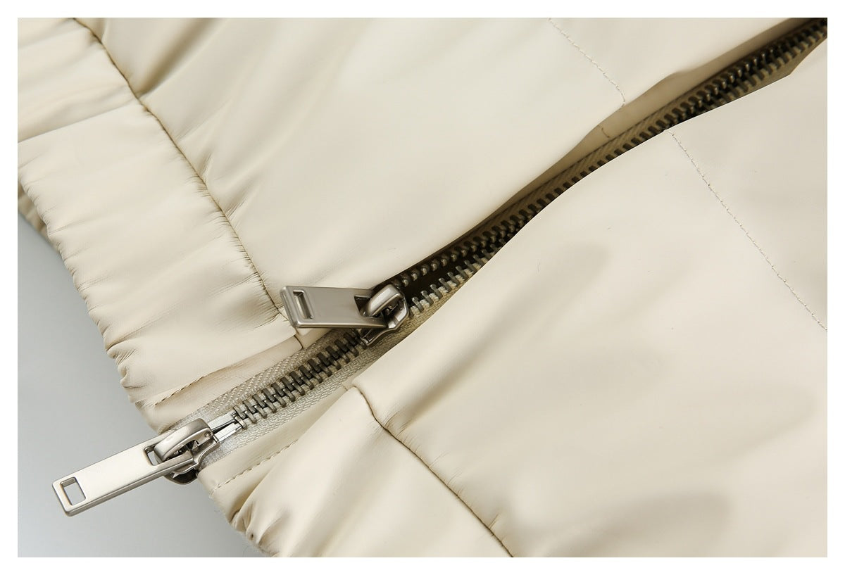 Close-up of a dark metal zipper with two pulls on a cream jacket, beside stitched padded sections.