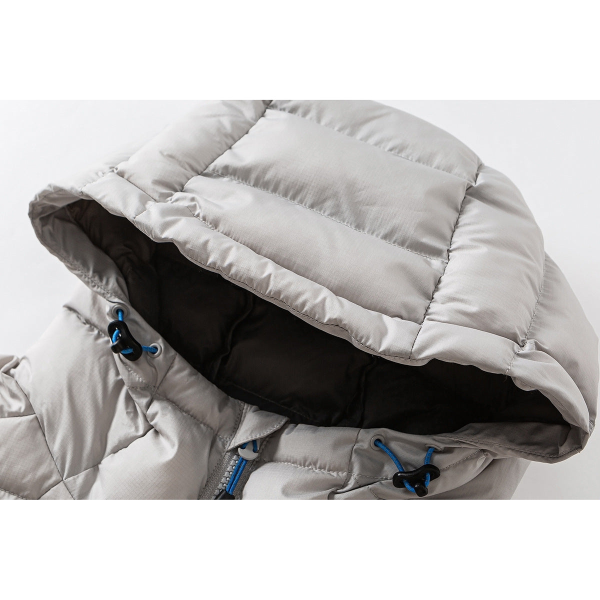 Close-up of a light gray quilted jacket hood with dark lining and blue drawcord toggles.