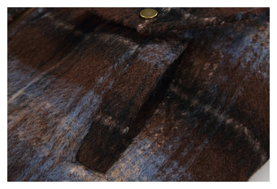 Close-up of a brown, blue, and black plaid coat with a brass-colored snap button.