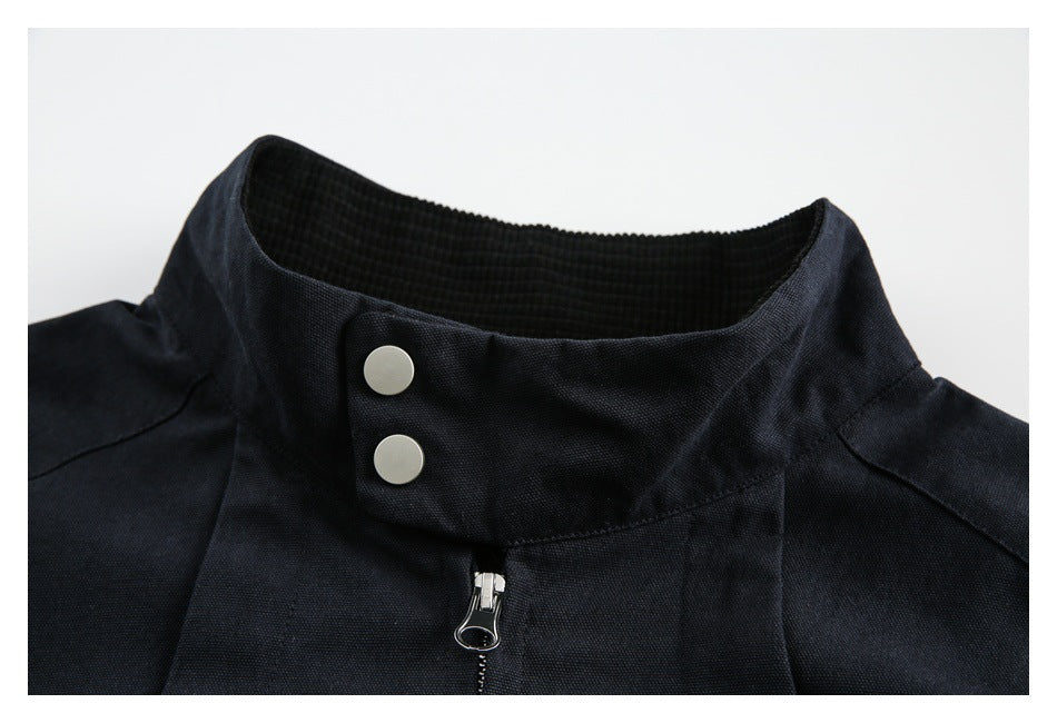 Close-up of a black jacket's stand collar, two metal snaps, and front zipper.