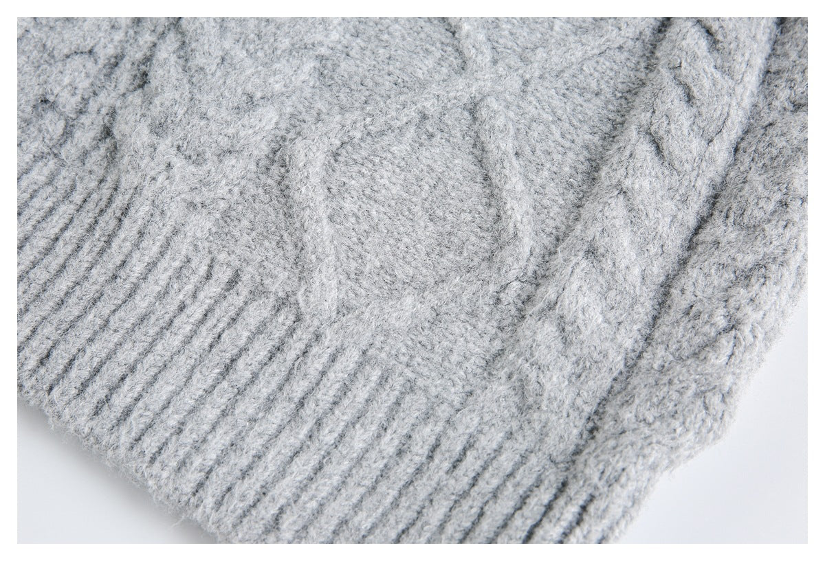 Close-up of a light gray sweater's textured knit and wide ribbed edge.