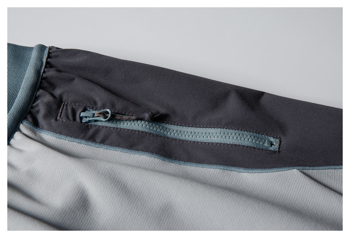 Close-up of a blue-gray zipper pocket on the dark side panel of the light gray pants.