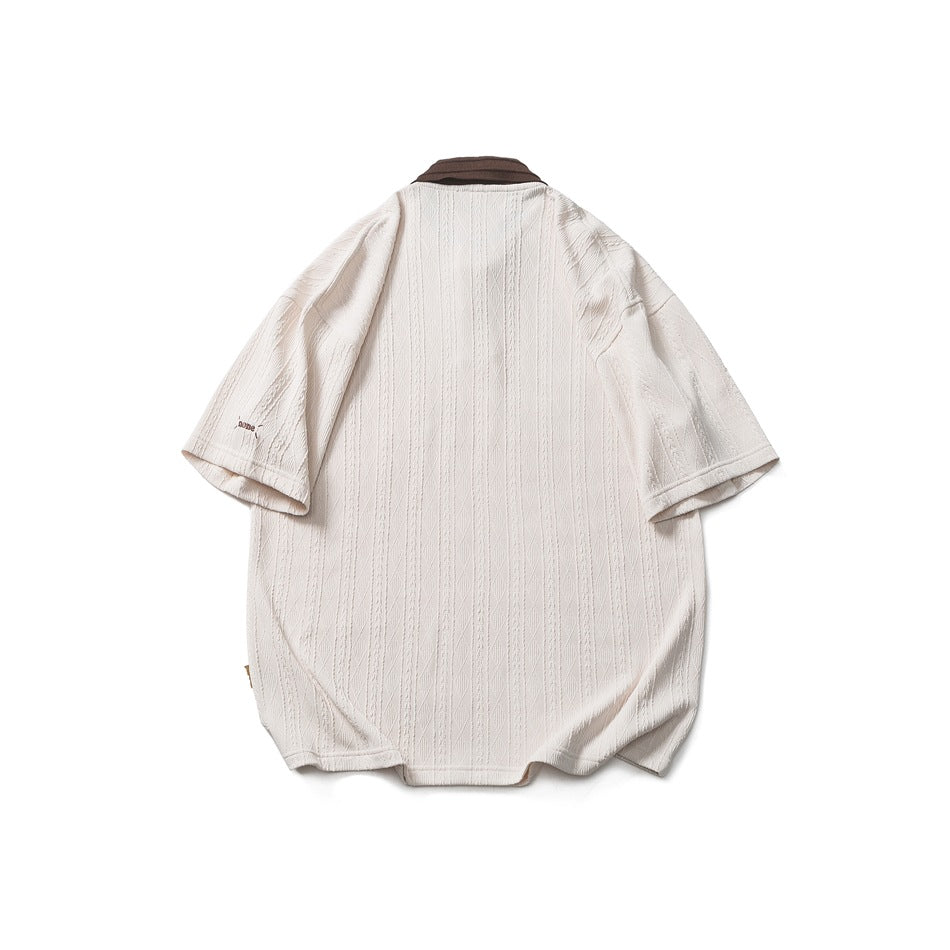 Back view of cream textured knit polo shirt with brown collar edge and small embroidered mark on the sleeve
