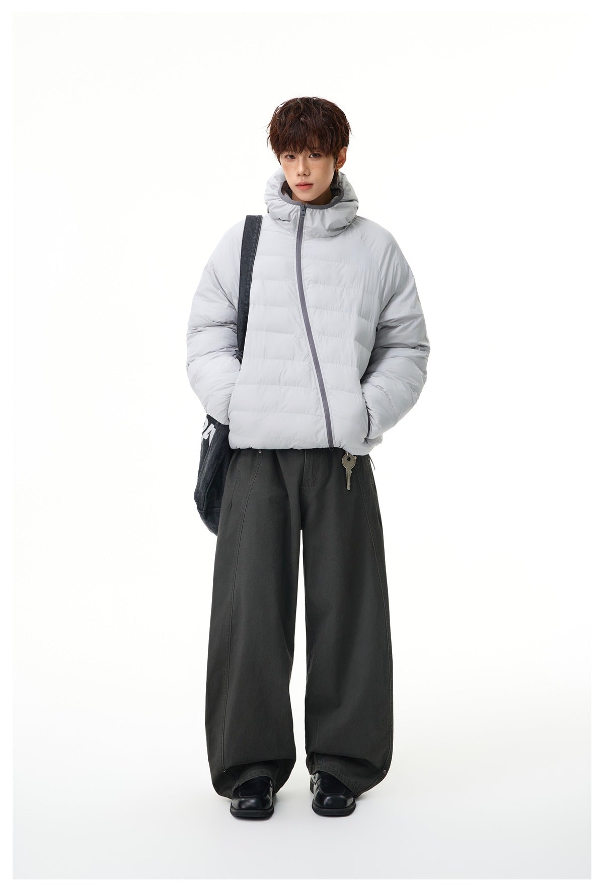 Full-length model wearing a light gray quilted hooded jacket with dark gray trim and wide-leg dark trousers.