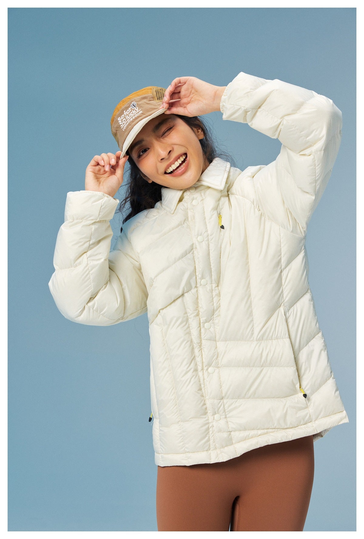 Close view of a model in an ivory quilted collared jacket with snap buttons and yellow zipper pulls.