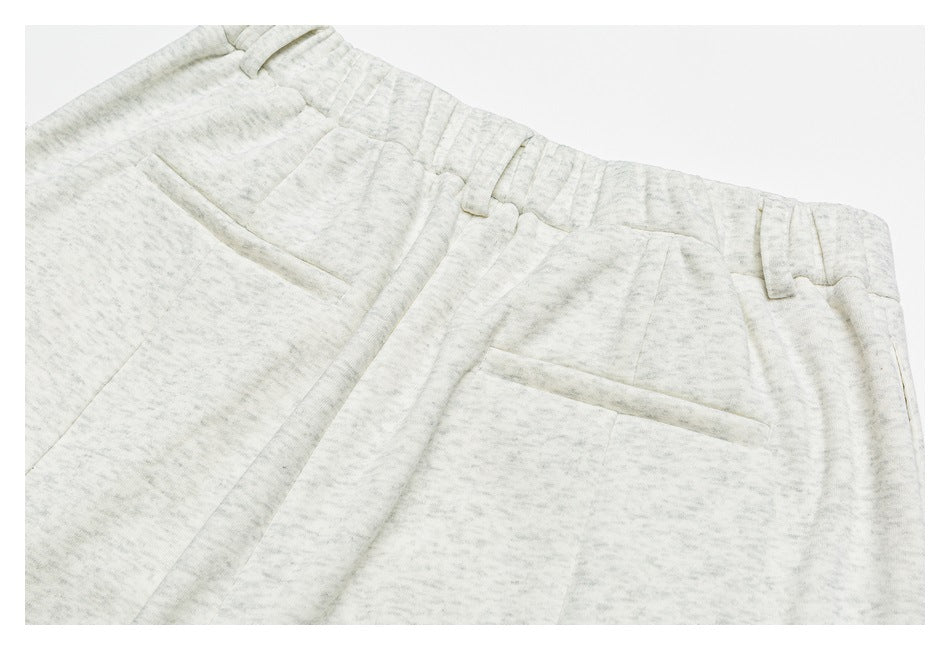 Close-up front view of light gray mottled trousers showing the waistband, belt loops, and slanted pockets.