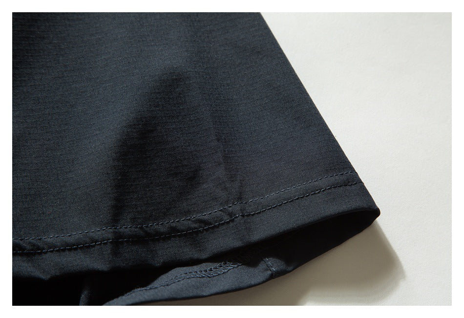 Close-up of a black garment hem with double stitching against a light background.