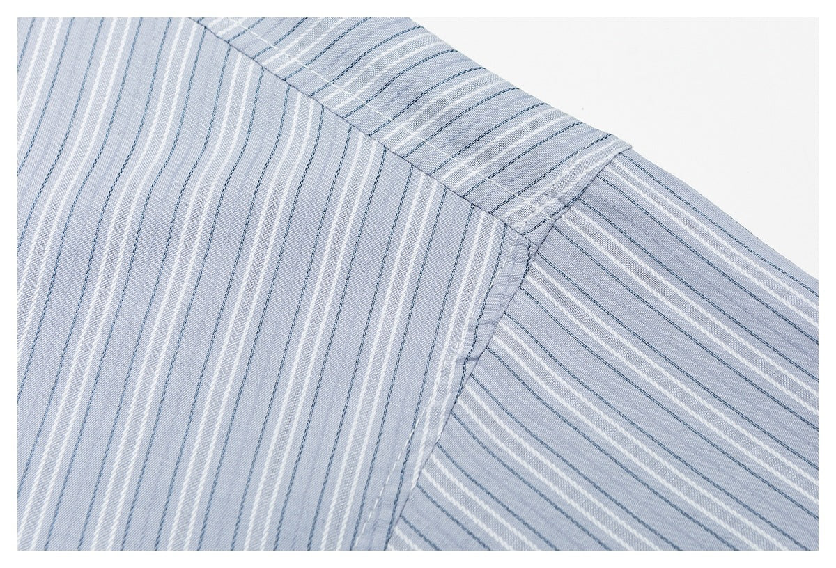 Close-up of the shoulder seam and sleeve on a pale blue shirt with fine white and dark blue stripes.